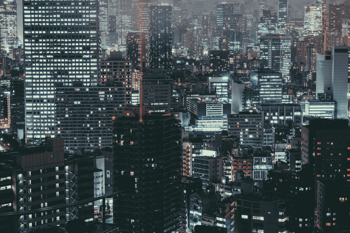 Rainy nighttime view over Shinjuku, Tokyo — squares of orange and white light out of the dark.