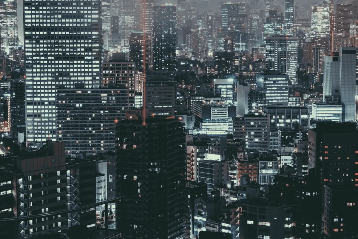 Rainy nighttime view over Shinjuku, Tokyo — squares of orange and white light out of the dark.